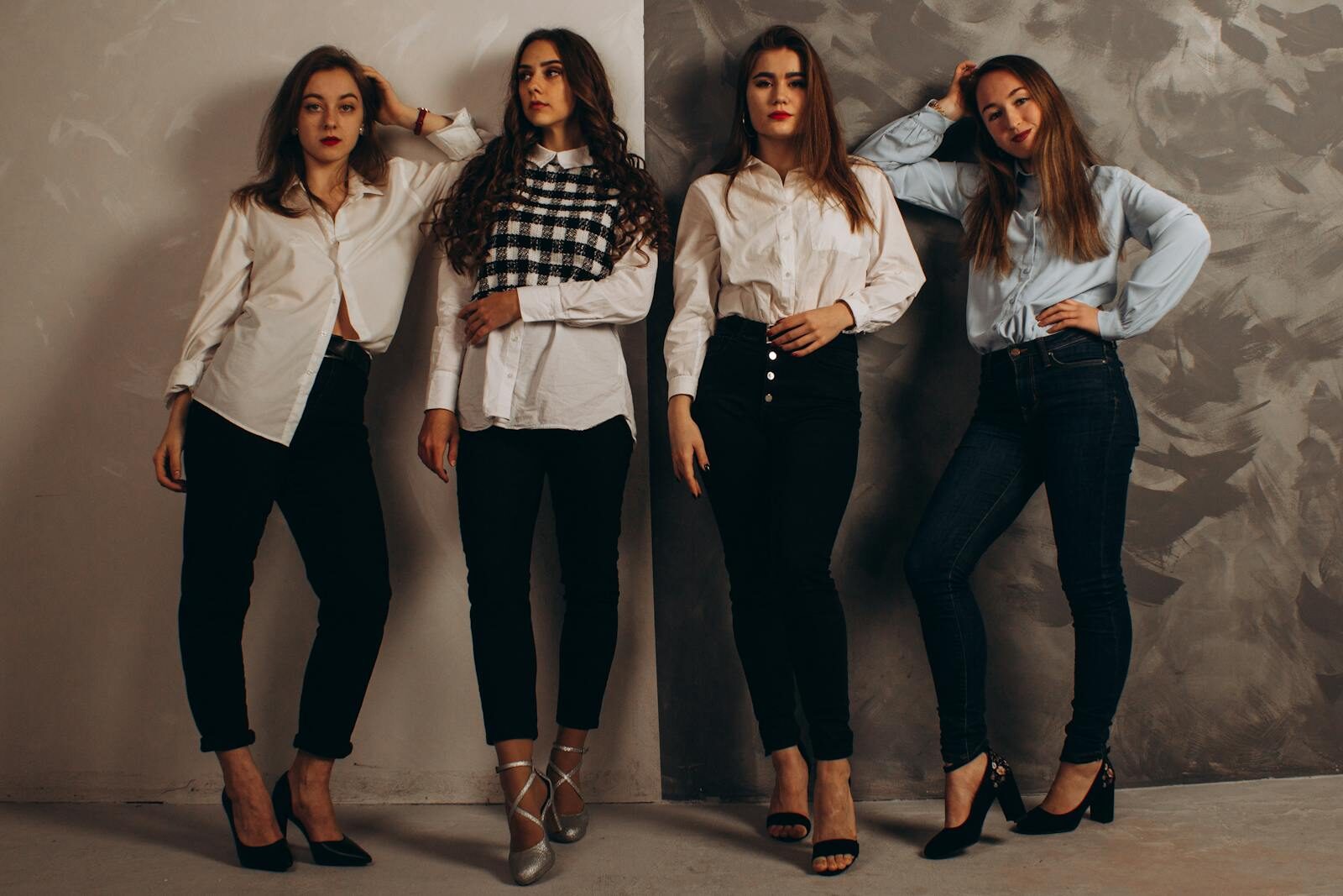 A group of fashionable women posing in a studio wearing smart casual outfits.